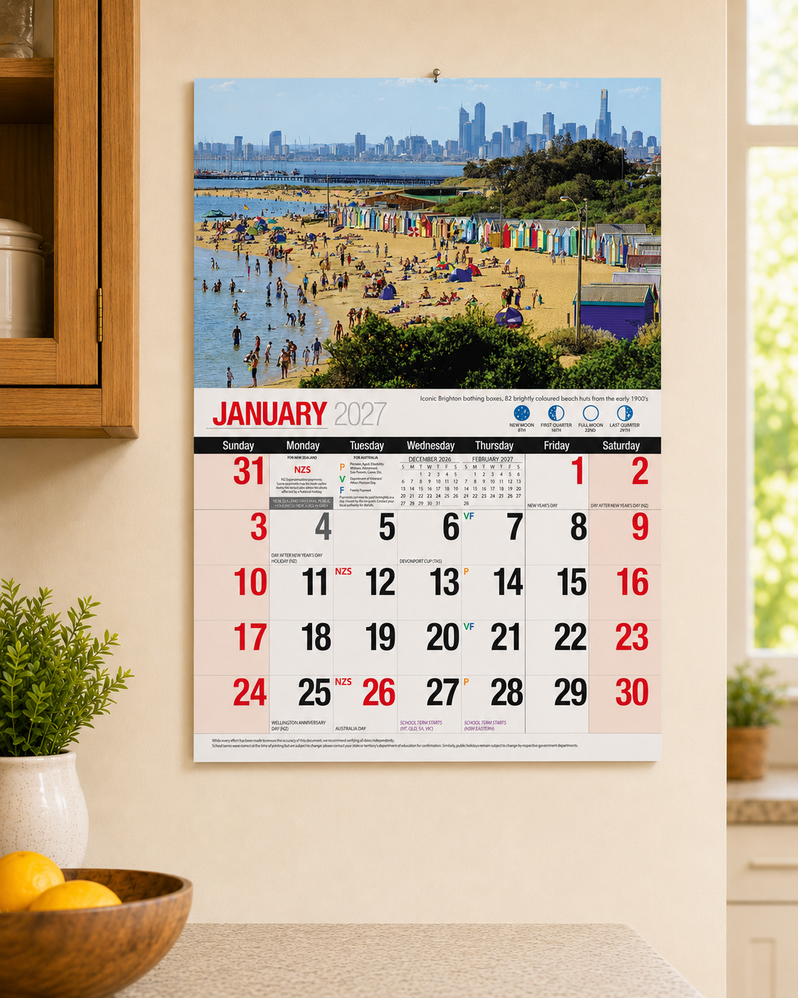 2027 Bartel Melbourne Wall Calendar displayed on kitchen wall showing January 2027 with Brighton bathing boxes