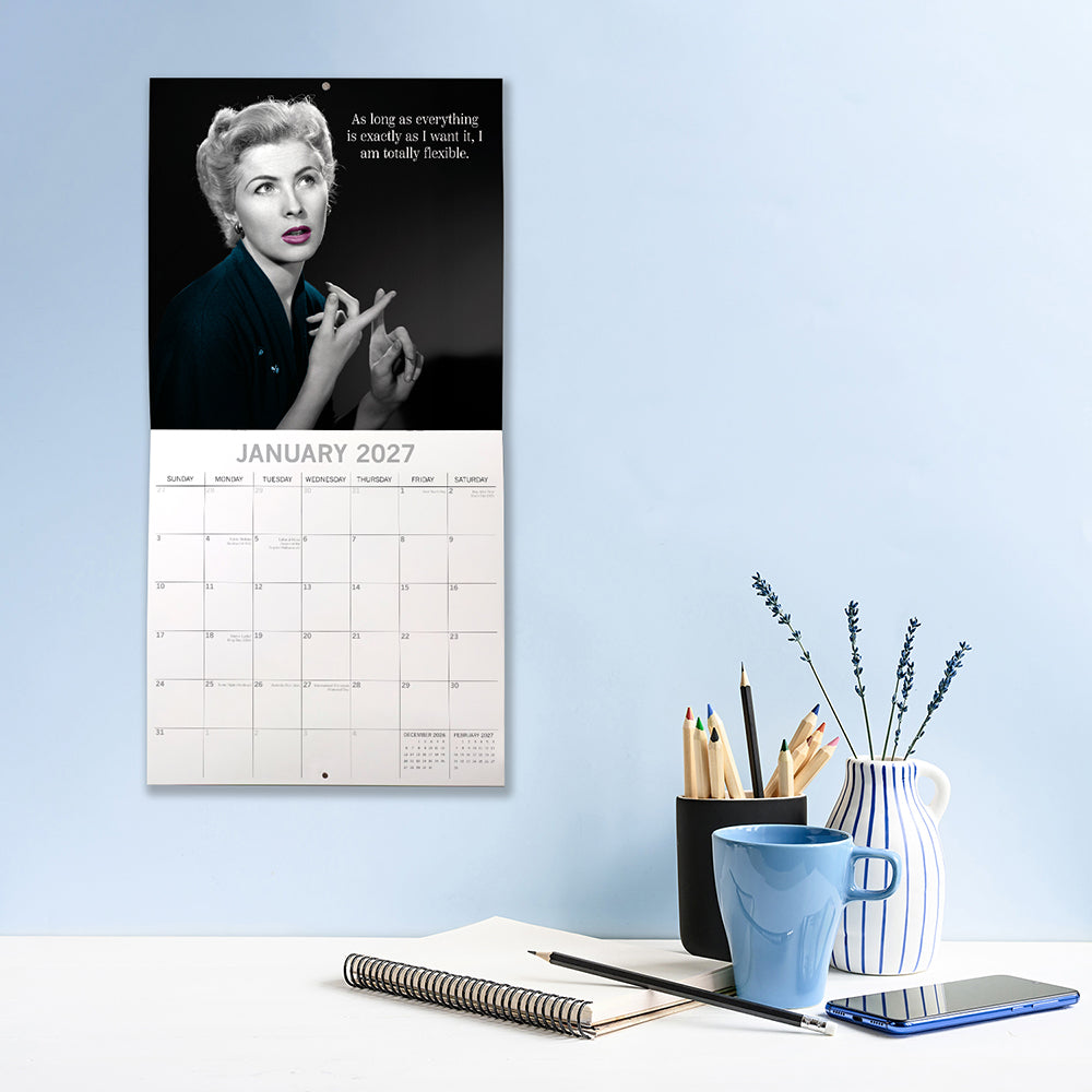 Women's Wit 2027 Calendar – January 2027 lifestyle shot on blue wall above desk featuring elegant woman with quote As long as everything is exactly as I want it I am totally flexible