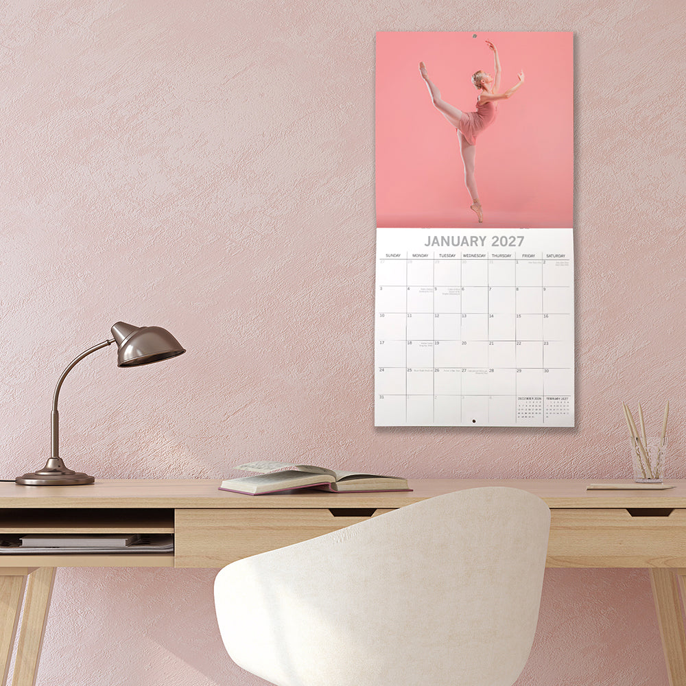 Ballet 2027 Square Wall Calendar - January 2027 lifestyle shot hung on wall above a styled home office desk with ballerina in pink