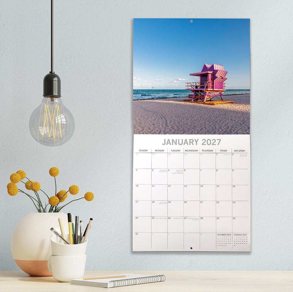 Beaches 2027 Calendar - lifestyle shot on wall showing January 2027 page with iconic pink lifeguard tower on Miami South Beach