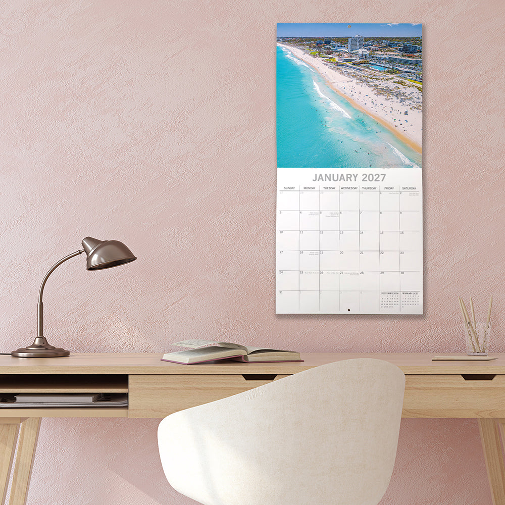 Coastlines of Australia 2027 Calendar - lifestyle shot on wall showing January 2027 page with aerial view of Cottesloe Beach, Perth, Western Australia