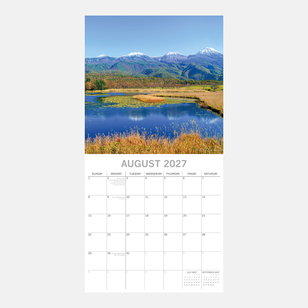 Japan 2027 Calendar - August 2027 page with snow-capped mountains of Hokkaido reflected in serene blue wetland lake with golden reeds