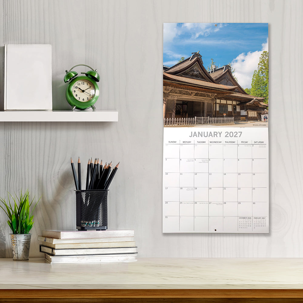 Japan 2027 Calendar - lifestyle shot on desk showing January 2027 page with traditional Japanese temple building under blue sky