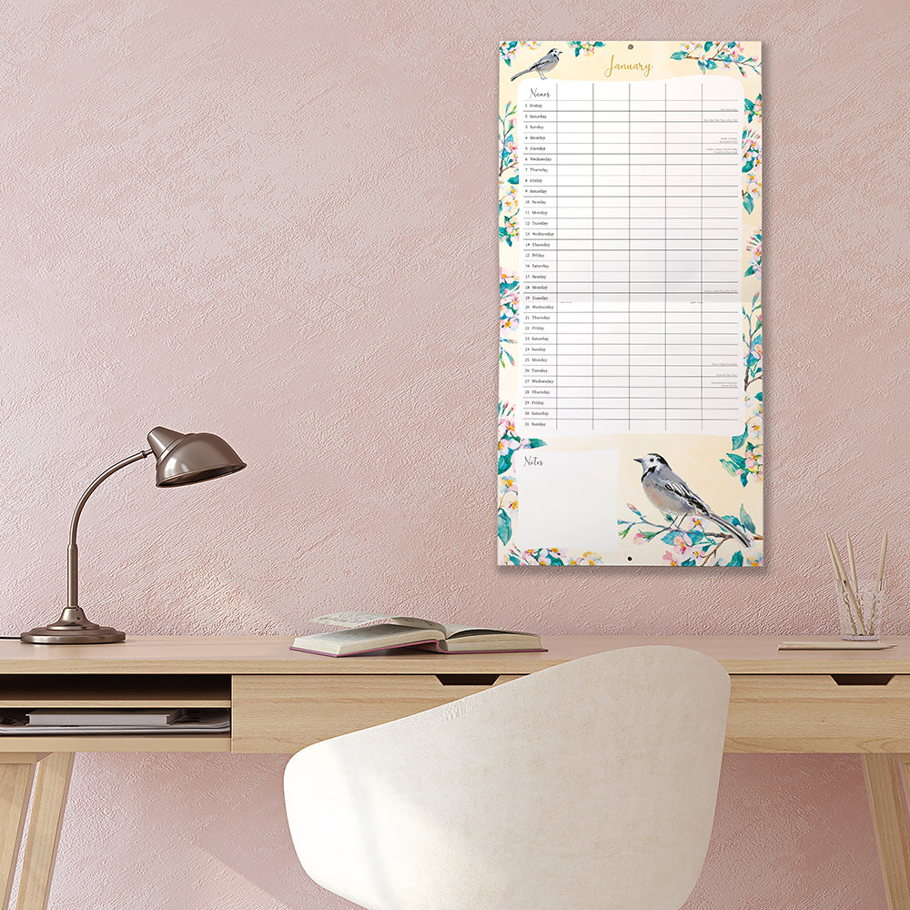 Birdsong 2027 Family Organiser Calendar – January 2027 lifestyle shot on pink wall above desk featuring Pied Wagtail watercolour with teal floral border