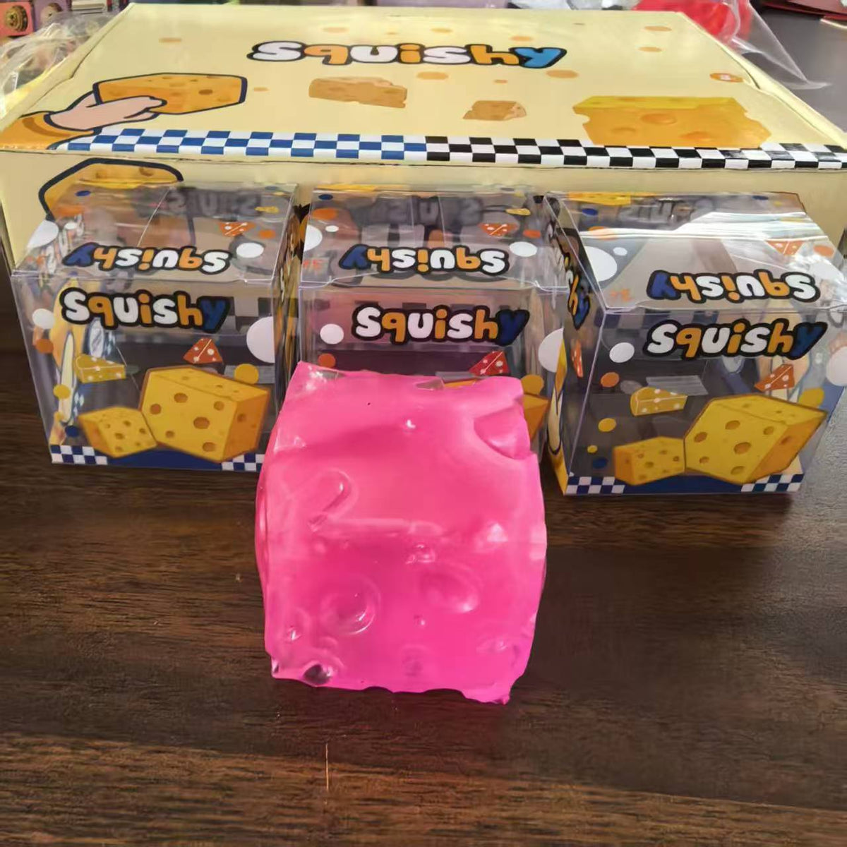 Purple cheese cube squishy held in a hand with other colours behind