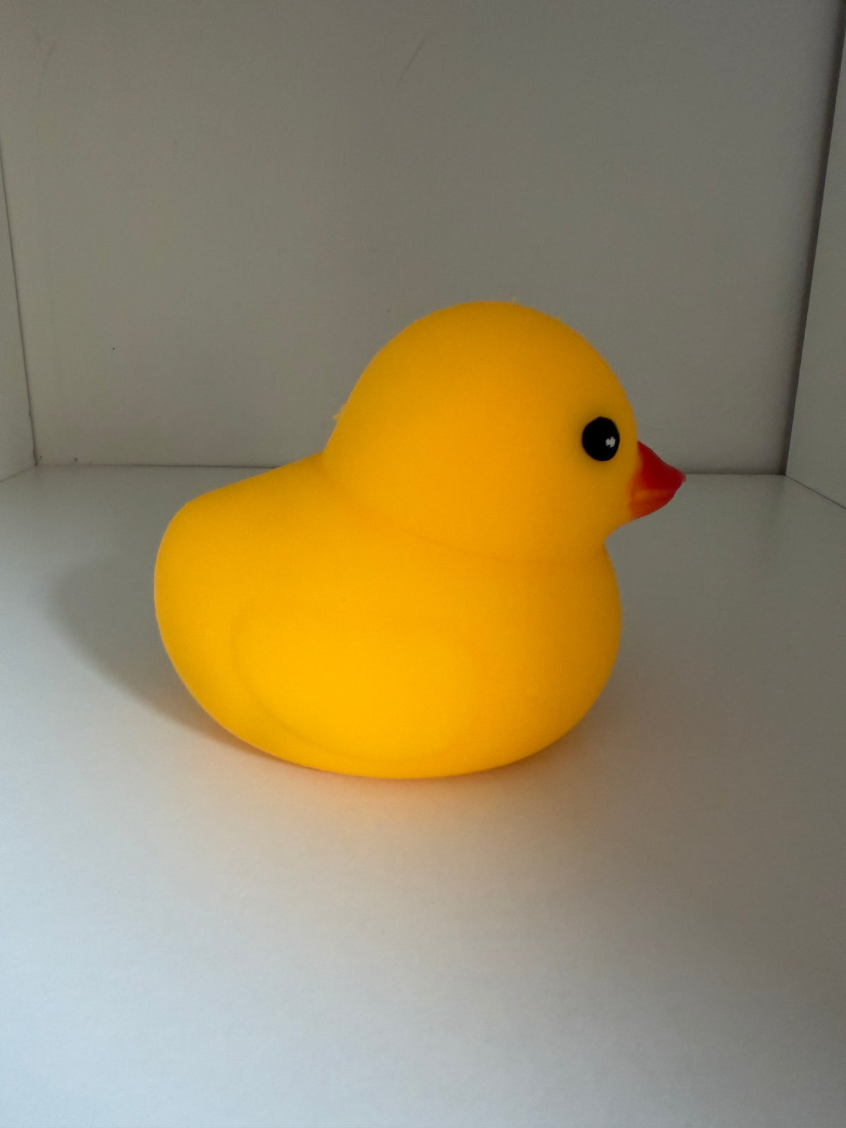 Side view of yellow sitting duck squishy on a shelf