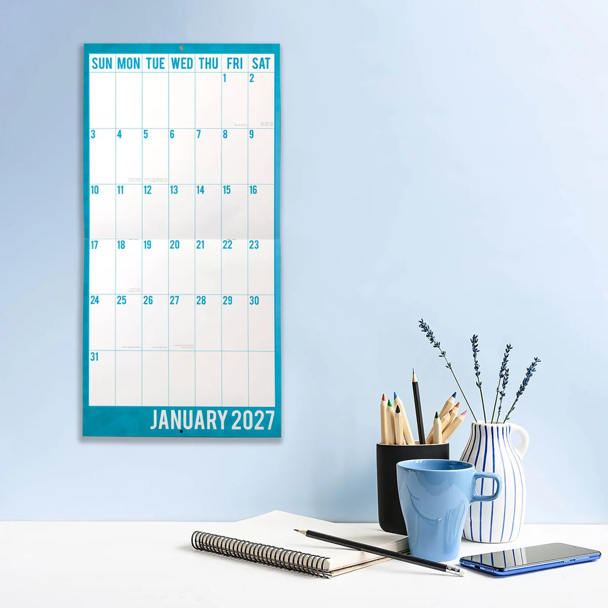 Large Print 2027 Square Wall Calendar - January 2027 lifestyle shot hung on wall above a home office desk with coffee mug and stationery