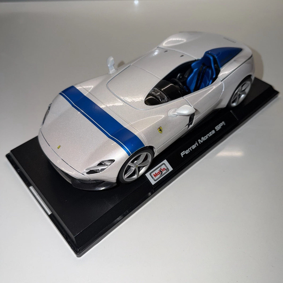 Side view of white Maisto Ferrari Monza SP1 model car with blue cockpit and labelled display base